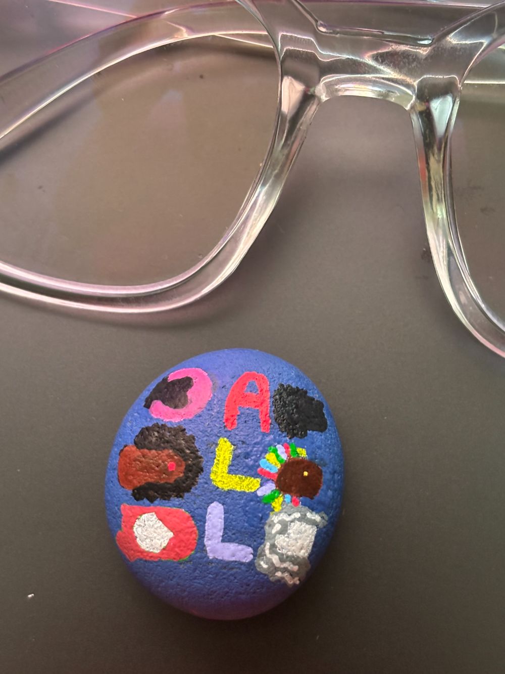 Hand-painted stone with colorful letters and characters